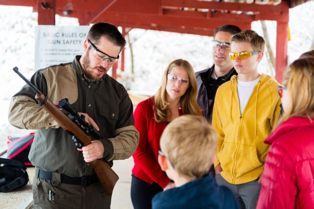 A firearms safety instructor is providing a demonstration to a family at a gun safety class