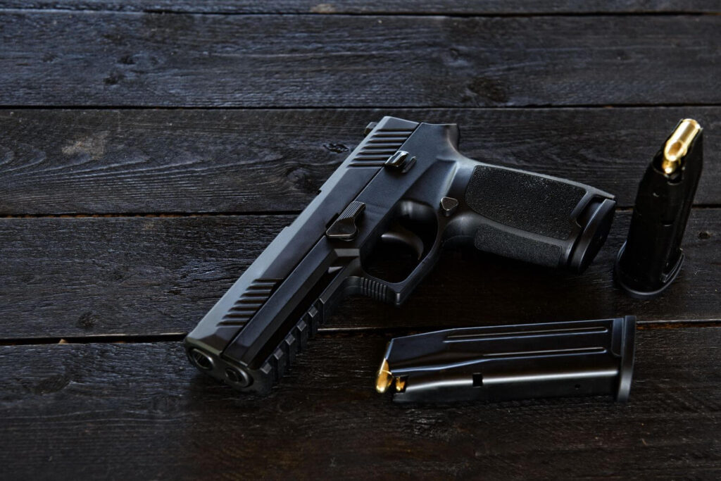 A small black pistol and two magazines placed on a dark wooden table