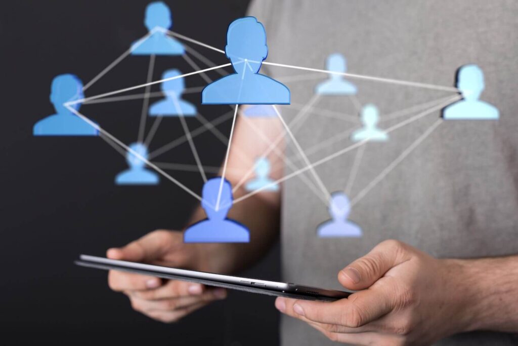 Hands holding a tablet and a blue graphic hovering above the tablet showing a network of people - Eastern Gun Expo Hands Holding a Tablet and a Blue Graphic Hovering Above the Tablet Showing a Network of People