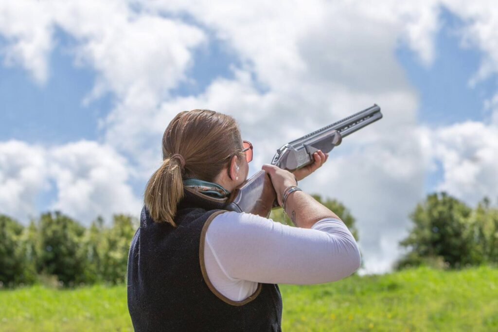 Woman clay shooting in a field - Eastern Gun Expo Woman Clay Shooting in a Field