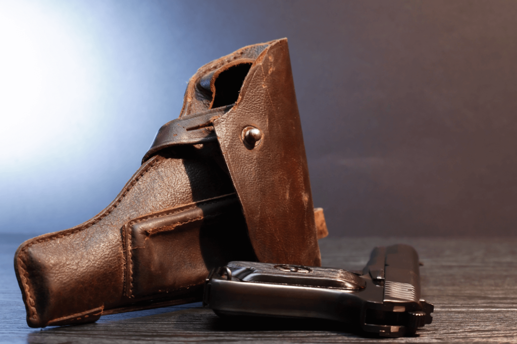 A leather gun holster and black gun on a table - Eastern Gun Expo a Leather Gun Holster and Black Gun on a Table