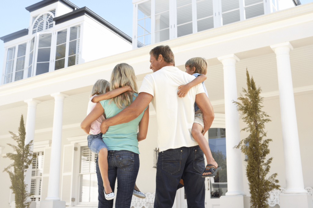 Family of four standing in front of their home