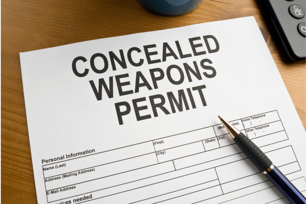 Paper that reads "concealed weapons permit" with a pen lying on it