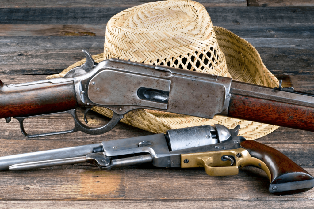 a Wooden Table with Two Antique Firearms and a Straw Hat Placed on It