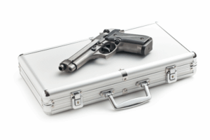 a Large Hard Silver Gun Case Closed with a Gun Lying on Top of It