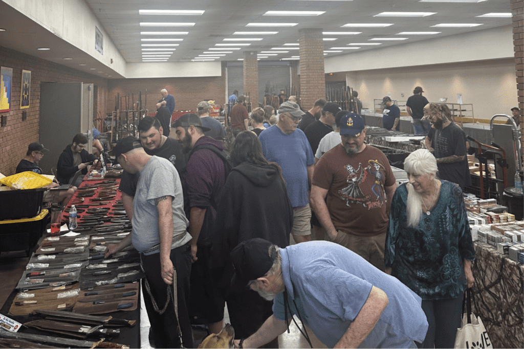 A gun show with tables set up and different people shopping around.